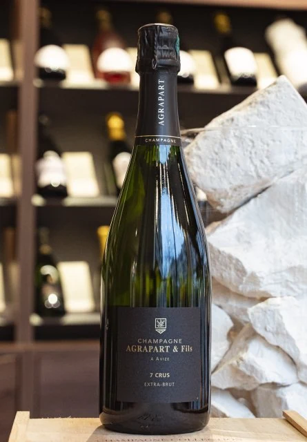 Photographie réelle : bouteille de champagne Agrapart & Fils, cuvée 7 Crus Extra-Brut, présentée sur une caisse en bois